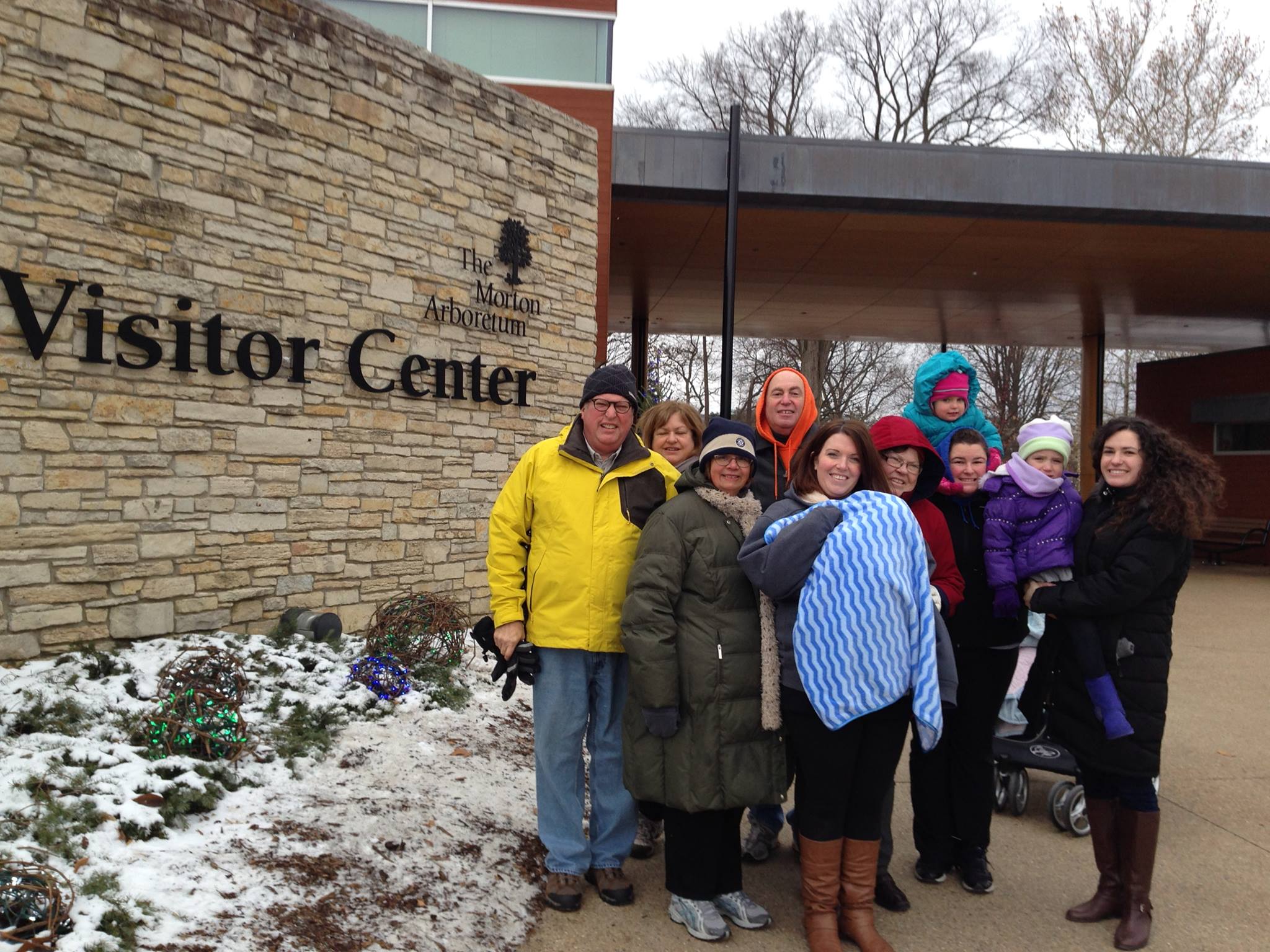 Family posing together in from of Visitor Center at The Morton Arboretum, with snow